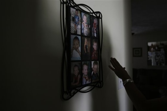 Joann Yost reaches for a display of photos of her son A.J. in Raeford, N.C., on May 14. Yost's husband Tony was killed in Iraq five years ago. 